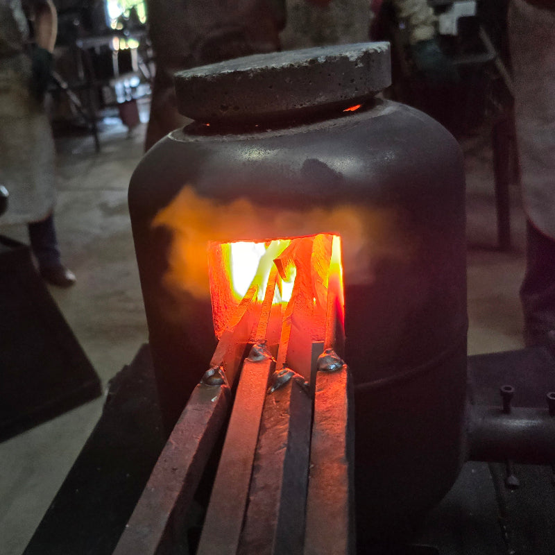 Hot metal object being worked on in a forge with flames visible