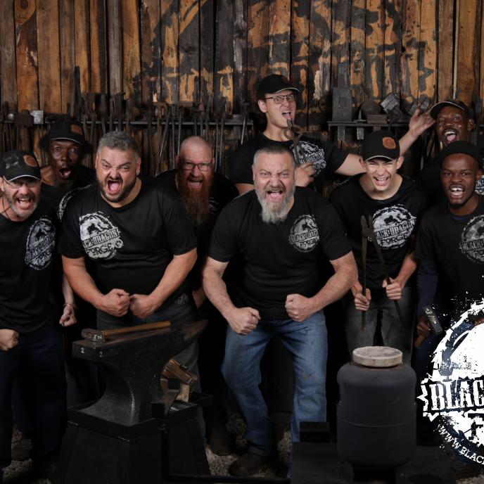 The Black Dragon Forge Crew in black t-shirts with a logo in a workshop setting, posing for a photo.