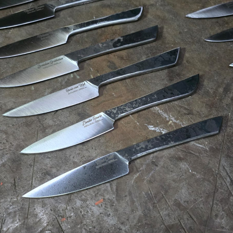 Black Dragon Forge Bladesmithing Experience  - Multiple student knives arranged on a textured surface