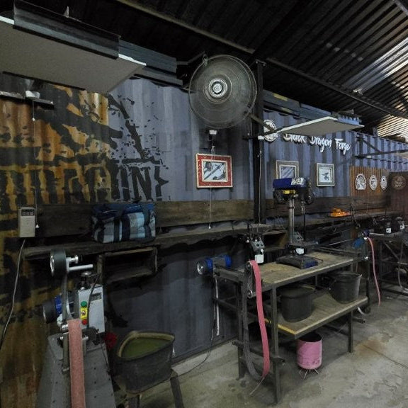 Black Dragon Forge Workshop with various tools and equipment on a concrete floor.