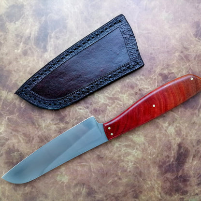 Knife with red handle and black sheath on a textured surface