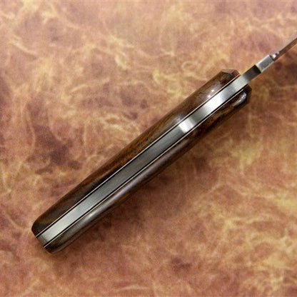 Knife with a brown handle on a brown leather surface