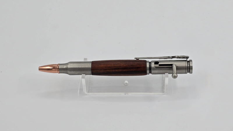 Bullet-shaped pen with wooden grip and metal accents on a clear stand against a light gray background