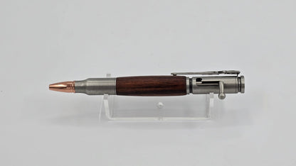 Bullet-shaped pen with wooden grip and metal accents on a clear stand against a light gray background