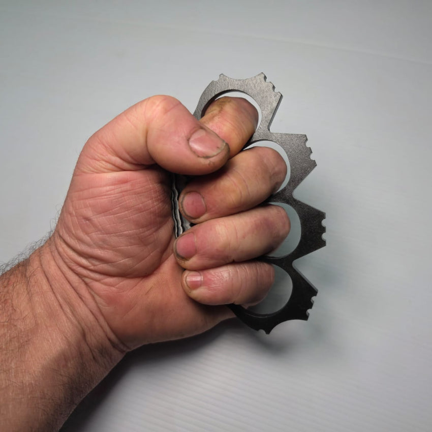Hand holding a knuckle duster against a plain background