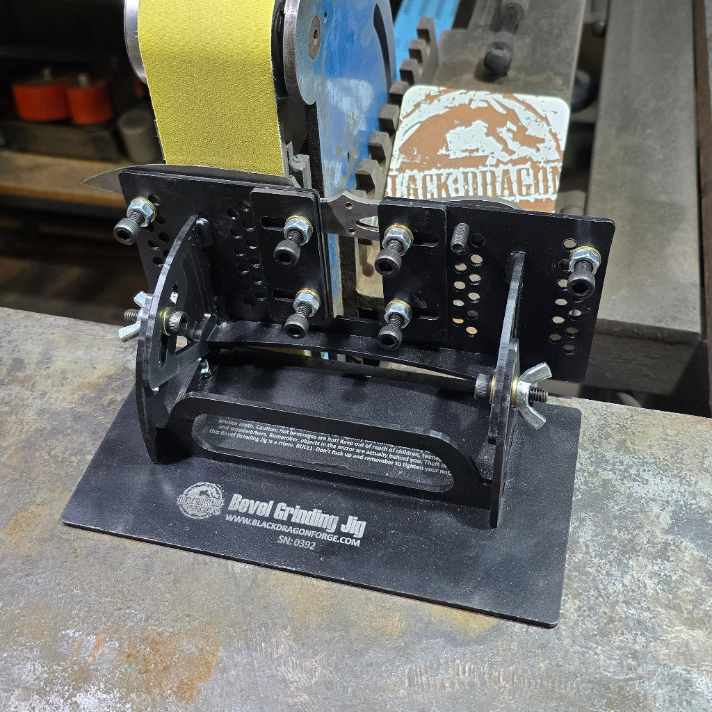 A black metal bevel grinding jig with bolts and adjustment screws, mounted on a workbench.
