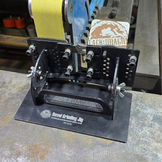 A black metal bevel grinding jig with bolts and adjustment screws, mounted on a workbench.