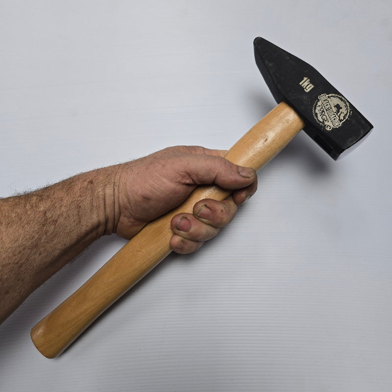Hand holding a hammer with a wooden handle and black head on a white background