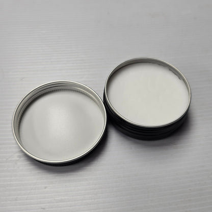 Two metal containers with lids on a textured gray surface